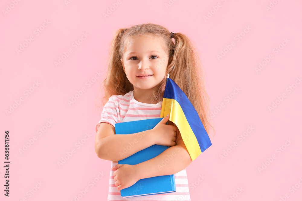 Happy little girl with Ukrainian flag and book on pink background Happy little girl with Ukrainian flag and book on pink background