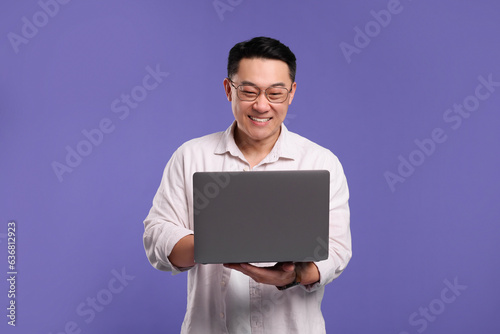 Happy man with laptop on lilac background