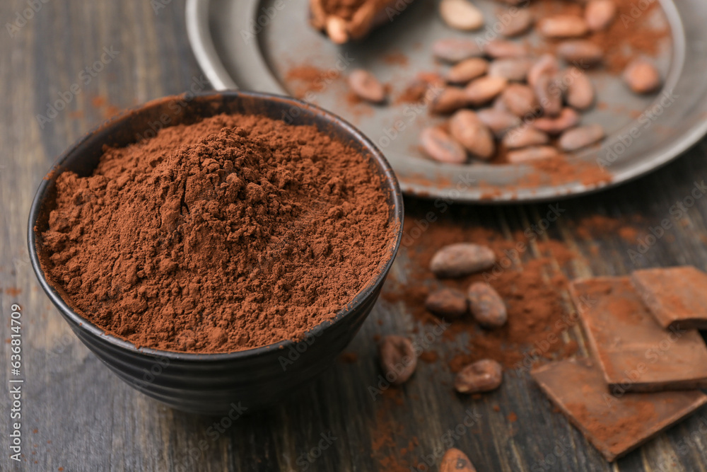 Bowl with cocoa powder on wooden background
