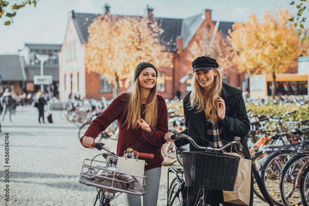 Young lesbian couple shopping and pushing their bicycles on a city street