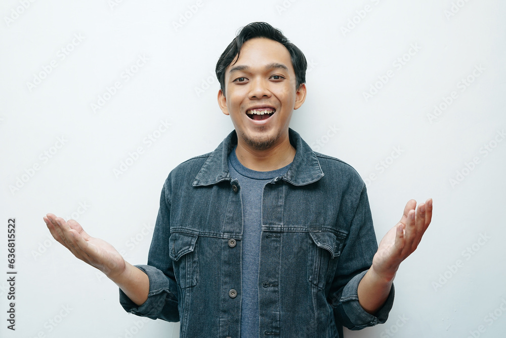 Portrait young Indonesian Asian man smiling while put hand palms in front of his body for presenting something. Isolated white background