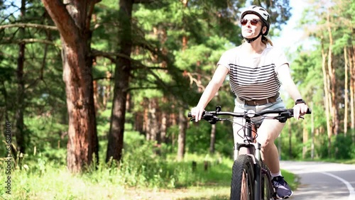 Pensive dreamful happy woman 40s wearing casual jeans short and tshirt riding bicycle bike in city summer park outdoors, look aside. People active urban healthy lifestyle cycling concept