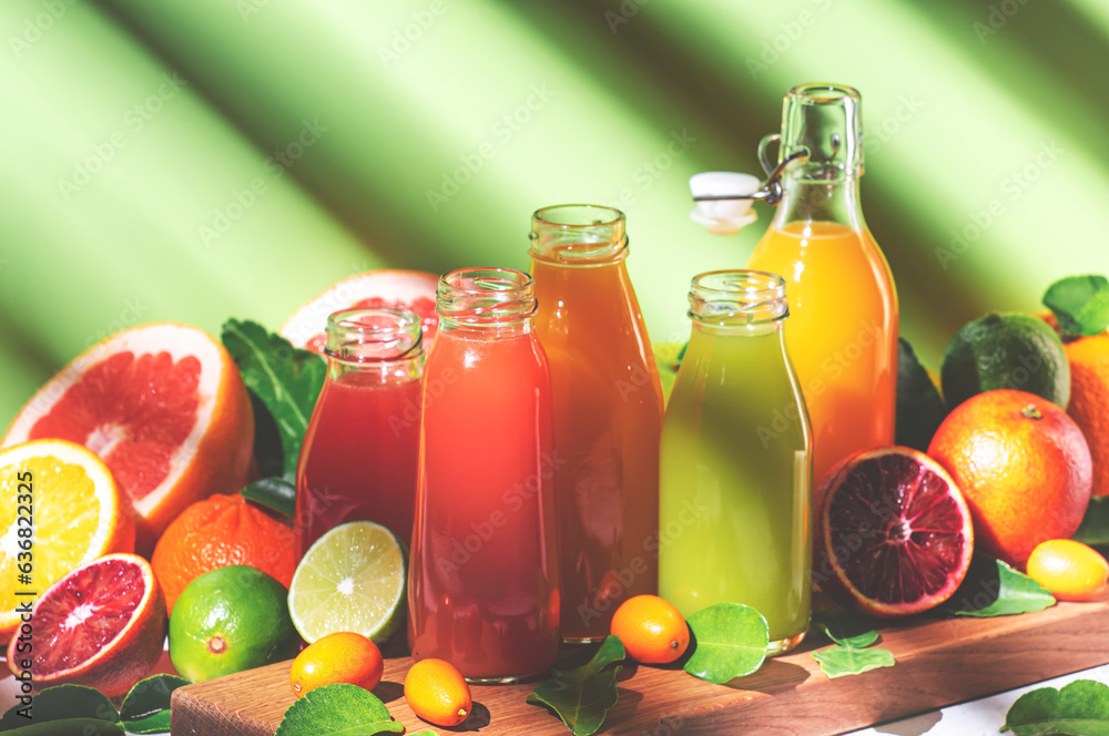 Citrus fruit juices, fresh and smoothies, food background. Summer drinks. Mix of different whole and cut fruits: orange, grapefruit, lime, tangerine with leaves and bottles with beverage Citrus fruit juices, fresh and smoothies, food background. Summer drinks. Mix of different whole and cut fruits: orange, grapefruit, lime, tangerine with leaves and bottles with beverage