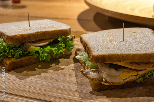 Foto von einem Sandwich mit Tomate, Ei, Gurke und Salat auf einem Brett mit Zahnstocher. Photo of a sandwich with tomato, egg, cucumber and lettuce on a board with toothpick