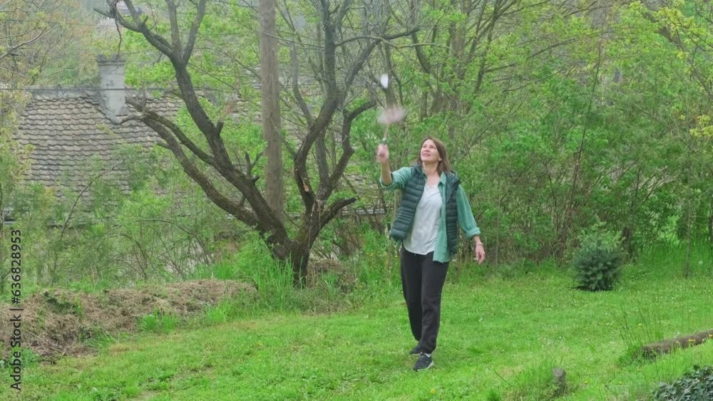 Woman relaxing in nature, playing badminton in a home garden. Female leisure activity outdoors. Child free weekend. Woman relaxing in nature, playing badminton in a home garden. Female leisure activity outdoors. Child free weekend.