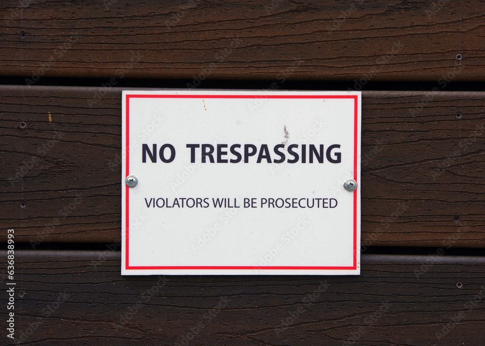 NO TRESPASSIGN sign on a wooden building wall NO TRESPASSIGN sign on a wooden building wall