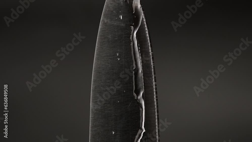 Water drop on sharp knife isolated on dark background. water splashing on knife.