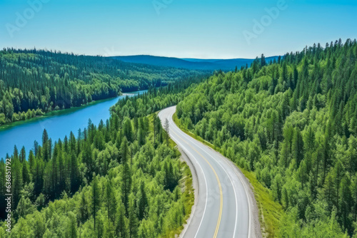 In the background is a blue sky in summer, a drone shot of a road in a forest area and a bend in a river, a beautiful landscape with grassy banks, a travel concept suitable for holidays and vacations.