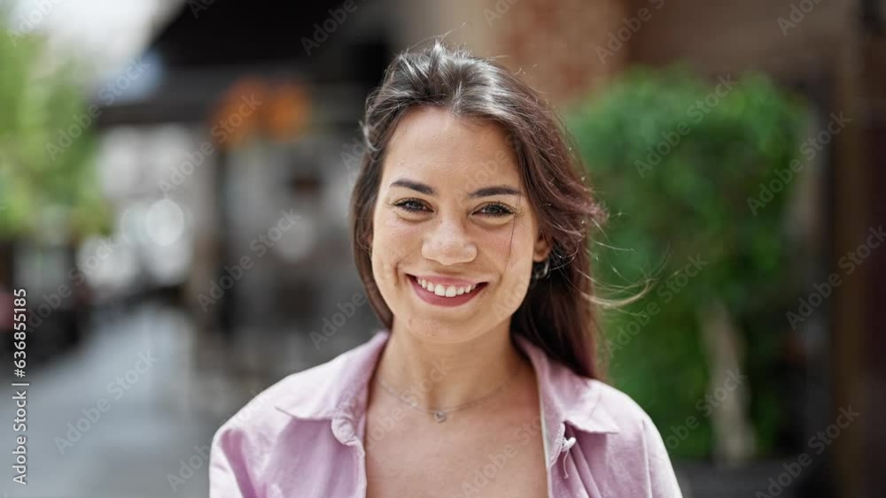 Young beautiful hispanic woman smiling confident combing hair with hand at street Young beautiful hispanic woman smiling confident combing hair with hand at street