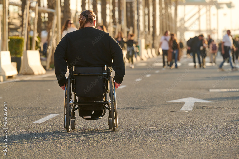 Obraz premium person in wheelchair at sunset on street in Malaga harbour in Spain