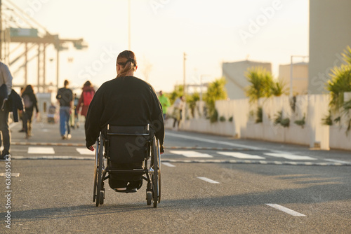 person in wheelchair at sunset on street in Malaga harbour in Spain © Lari