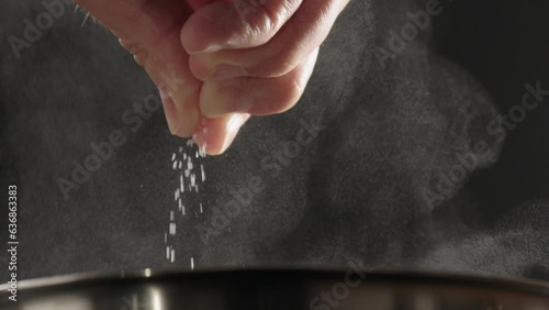 Slow motion man add salt into pot wit steam rising
