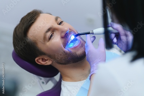 Closeup portrait patient in dental office - ultraviolet light equipment photo