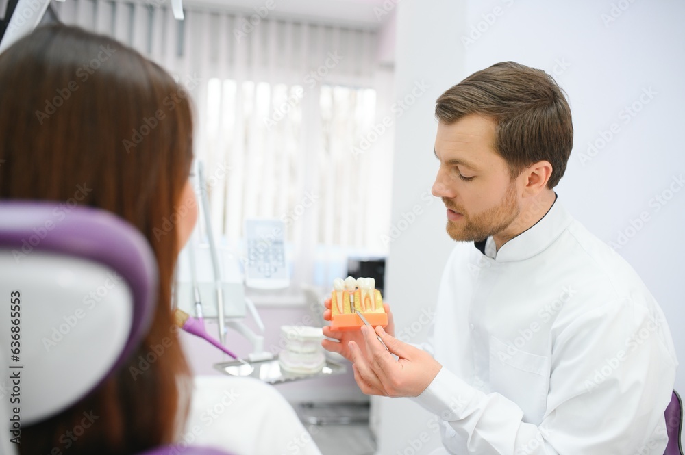 Doctor shows on a plastic tooth sample or model different methods of teeth treatment