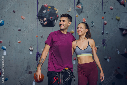 A strong couple of climbers against an artificial wall with colorful grips and ropes.