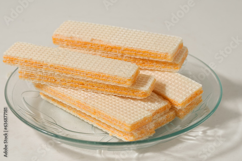 Several wafer biscuits served on a small plate isolated on a white background.