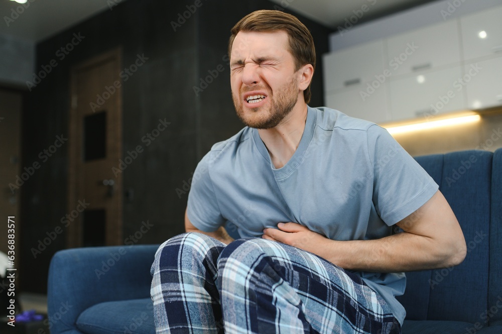 Young man suffering from stomach ache at home Young man suffering from stomach ache at home