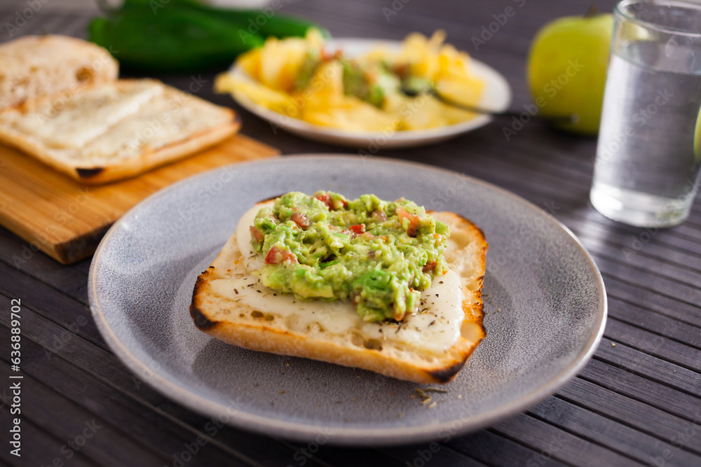Tasted slices of square bread with warm cheese and homemade guacamole on a plate Tasted slices of square bread with warm cheese and homemade guacamole on a plate