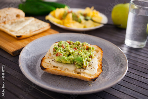 Tasted slices of square bread with warm cheese and homemade guacamole on a plate