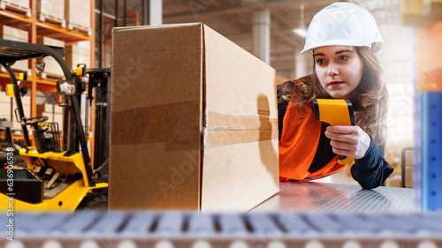 Storekeeper with laser scanner. Warehouse worker woman. Girl scans barcode on box. Warehouse accounting system. Woman storekeeper in protective helmet. Logistic warehouse. Supervisor, contractor