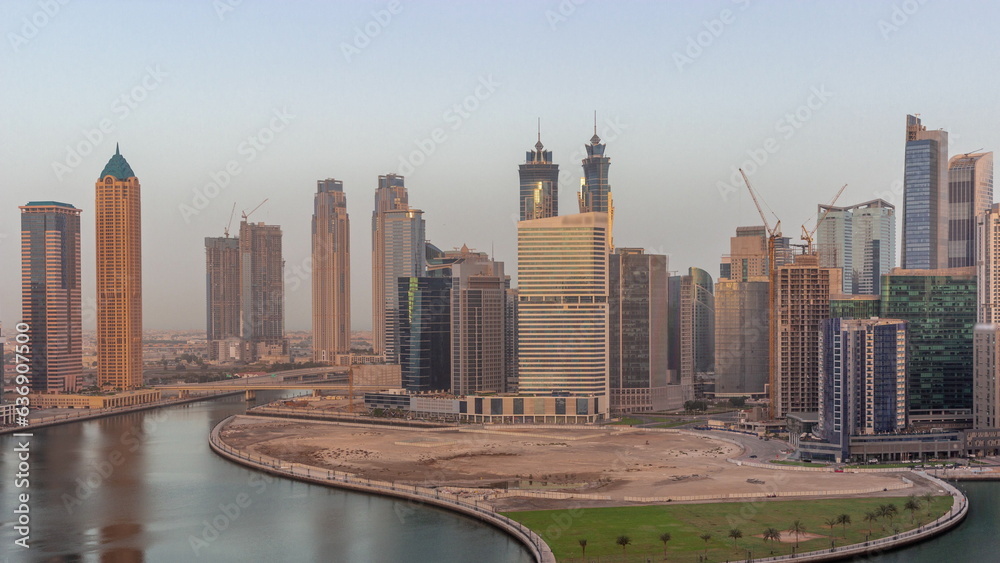 Cityscape of skyscrapers in Dubai Business Bay with water canal aerial night to day timelapse