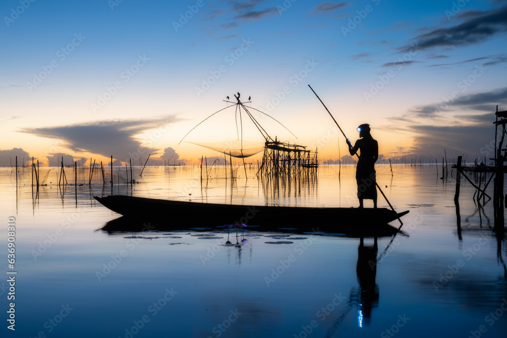 Silhouette image of fisherman go fishing in the morning during sunrise time at Pak Pra, Phatthalung in Thailand. 