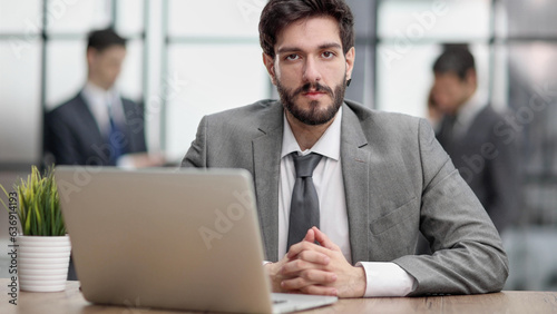Thoughtful businessman pondering ideas or strategy, sitting at wooden with laptop,