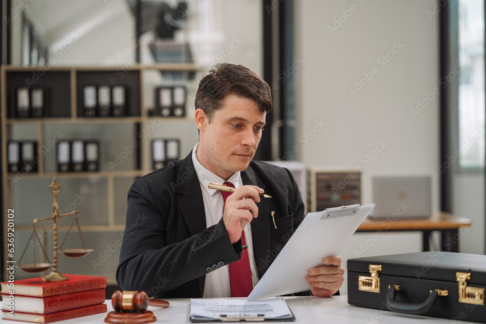 Justice and law concept. male judge in a courtroom with the gavel working with digital tablet computer docking keyboard on table. Justice and law concept. male judge in a courtroom with the gavel working with digital tablet computer docking keyboard on table.