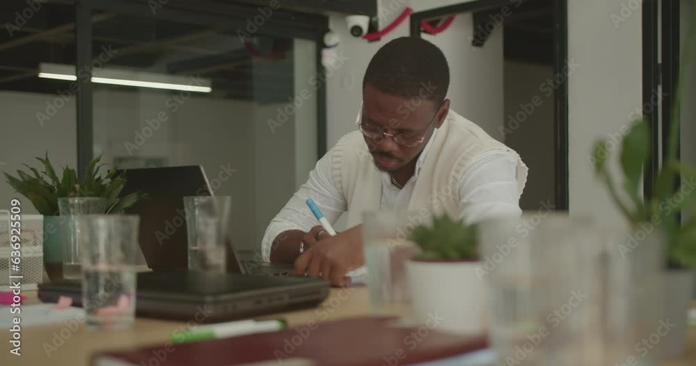 Black male working alone in the office while his colleagues are on a break Black male working alone in the office while his colleagues are on a break