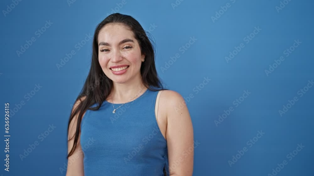 Young beautiful hispanic woman smiling pointing to the side with finger over isolated blue background Young beautiful hispanic woman smiling pointing to the side with finger over isolated blue background