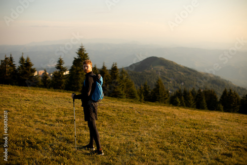 Young man walking with backpack over green hills © BGStock72