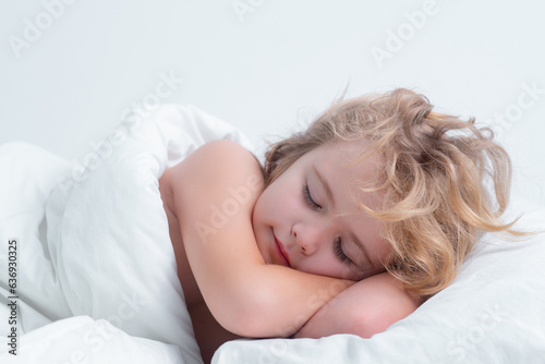 Kid sleeping in cozy white bed. Cute child sleeping on bed at home. Bedtime, kid sleeps. Kid asleep on soft pillow with blanket having healthy sleep.