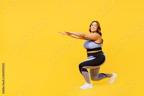 Full body sideways young chubby plus size big fat fit woman wear blue top warm up training do squats lunges raise up hands isolated on plain yellow background studio home gym. Workout sport concept.