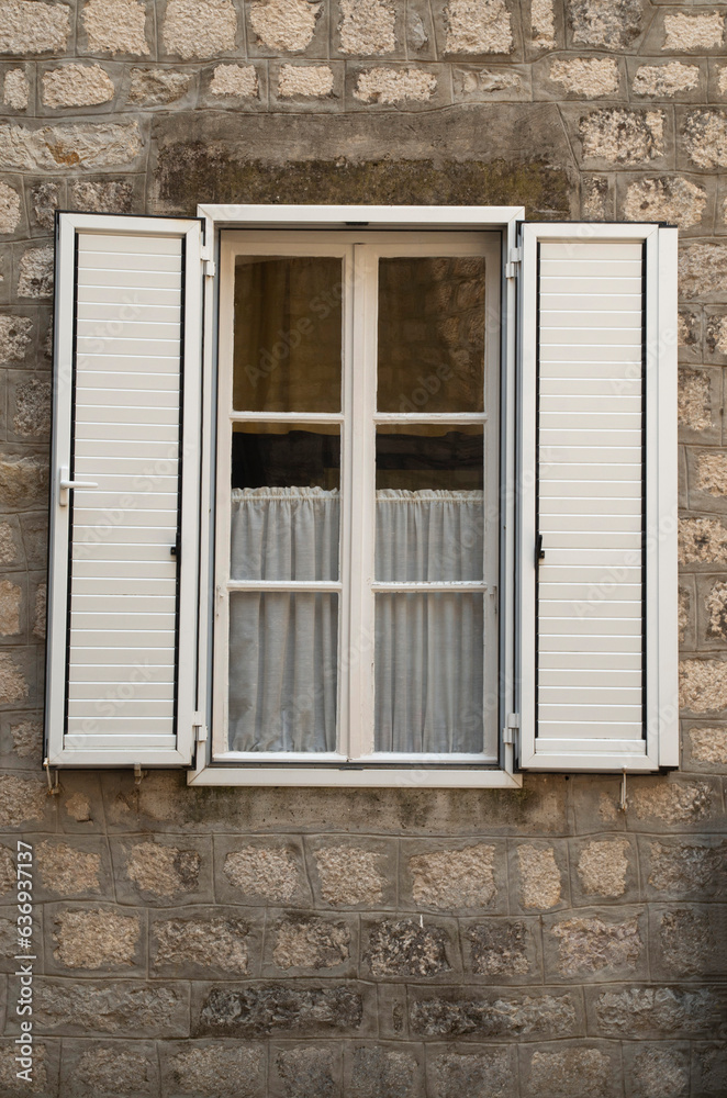Fototapeta premium Traditional new white window shutters as blinds on old stone home
