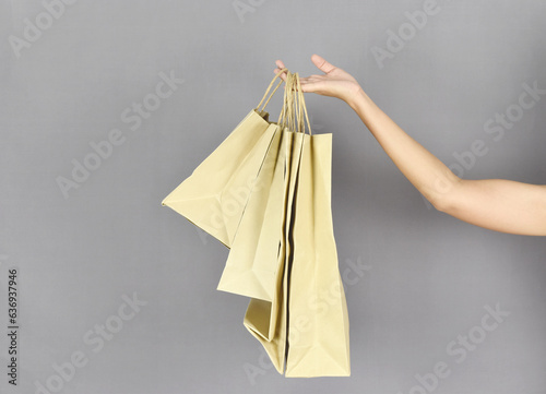 Woman hand holding shopping bags on grey background.