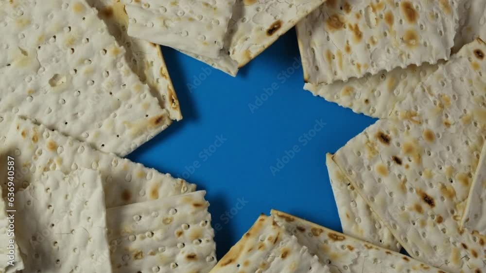 Matzah or Matzo kosher food on blue background with David Star. Jewish traditional Passover bread. Pesach celebration symbol. 4K Video, Rotating.