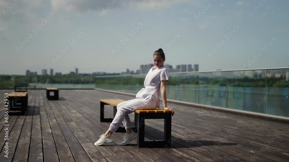 Girl posing on a bench in the open sun. Slow motion. Summer cityscape. Girl posing on a bench in the open sun. Slow motion. Summer cityscape.