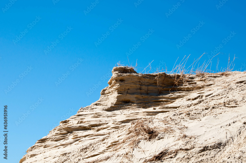 Sand dunes on the seashore against the blue sky.