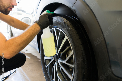 Auto detail service worker cleaning undercarriage of car photo