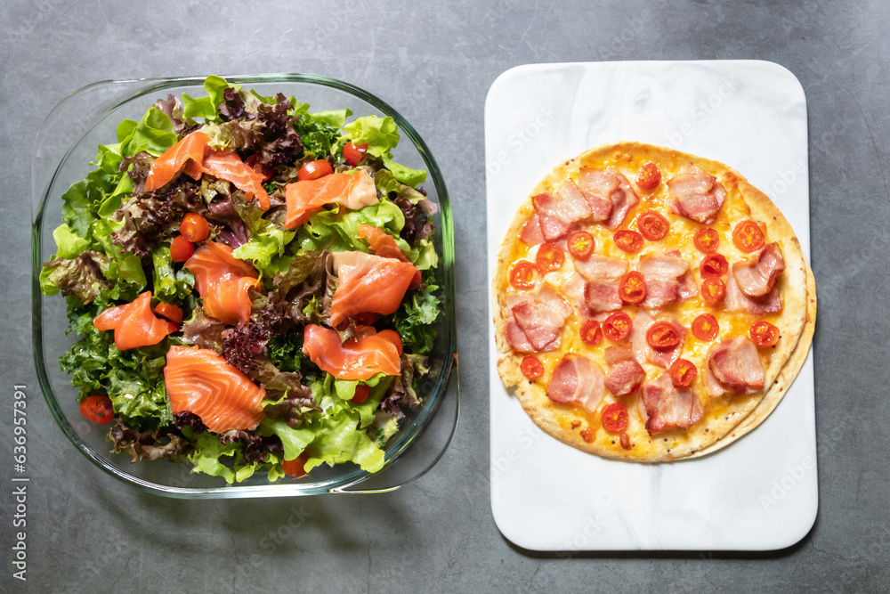 Delicious gourmet pizza smoke bacon, cheese and tomato with smoke salmon salad on black table background. Homemade delicious pizza. Top view and copy space. Delicious gourmet pizza smoke bacon, cheese and tomato with smoke salmon salad on black table background. Homemade delicious pizza. Top view and copy space.