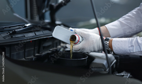 Close-up of professional mechanic in protective gloves pouring quality oil to car engine. Refueling transport. Energy fuel and automobile maintenance concept