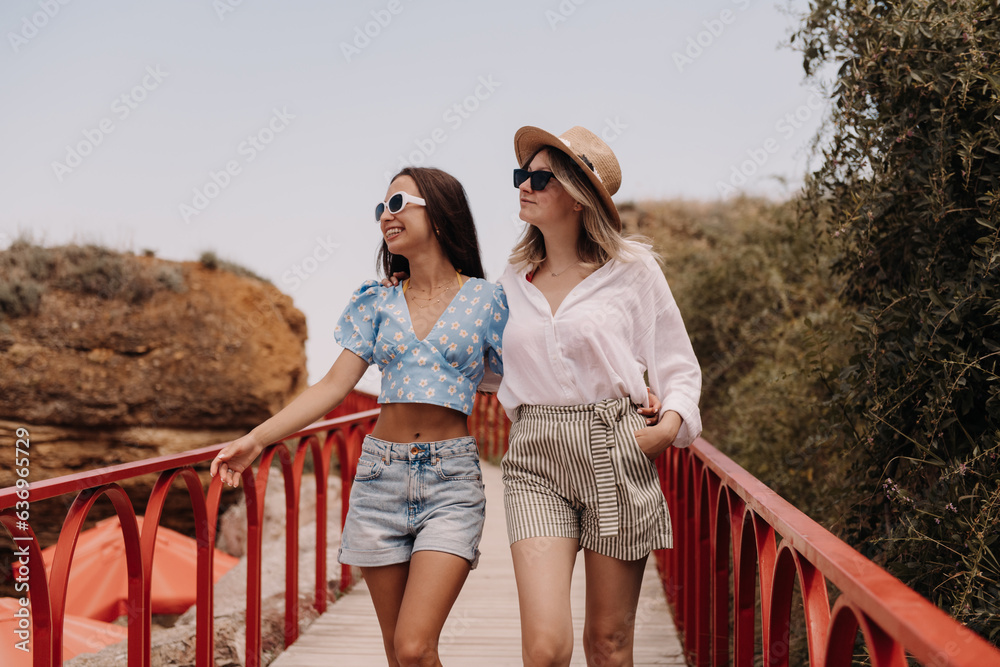 Two fashionable young women embracing and smiling while walking outdoors together