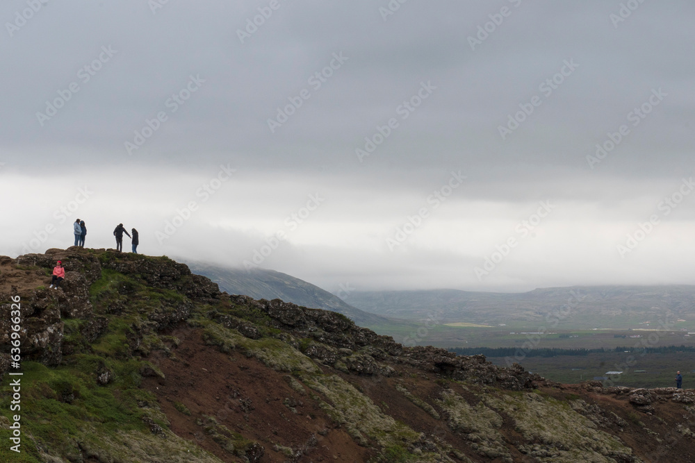 People walking on upper ridge of the volcanic Kerid Crater overlooking the crater lake in the Grimsnes area of South Iceland. 