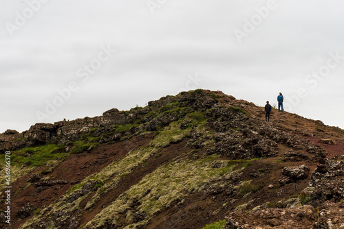 People walking on upper ridge of the volcanic Kerid Crater overlooking the crater lake in the Grimsnes area of South Iceland.  photo