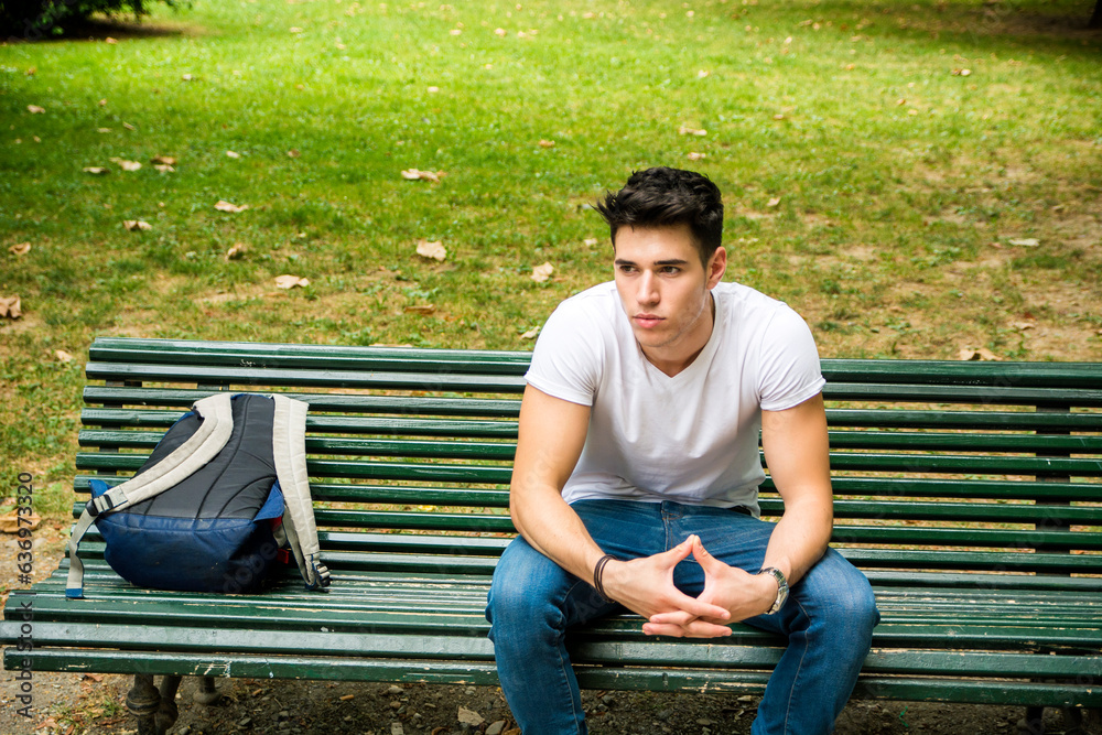 Obraz premium Photo of a man sitting on a bench with a backpack