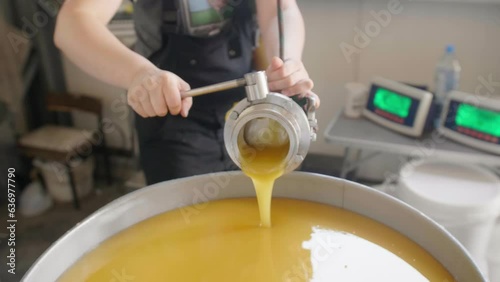 Factory worker feeling a barrel with homogenized honey with many barrels on the background photo