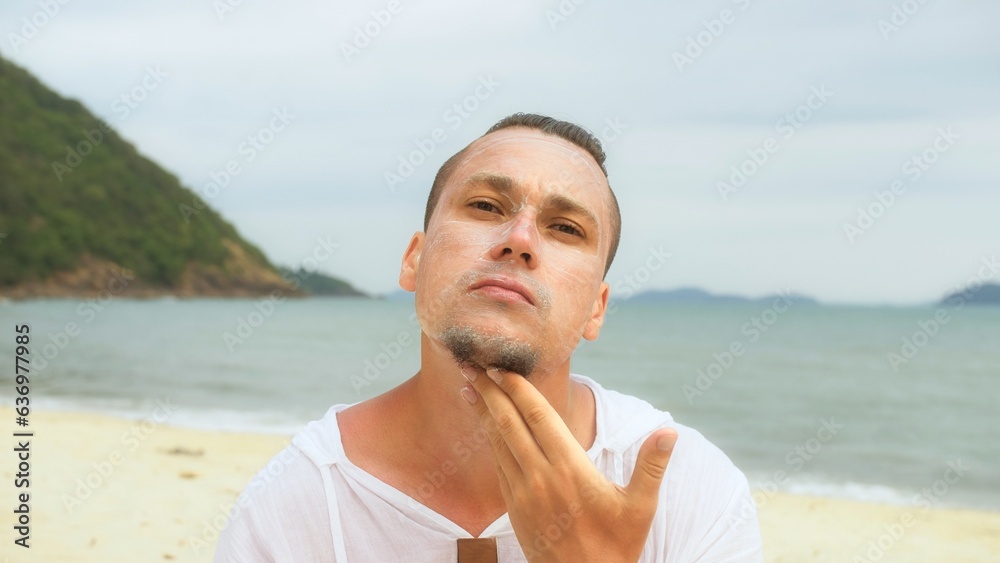Portrait man apply sun cream protection lotion.Man looking at camera, relax on beach near sea smearing sunscreen cream on face.Concept facial beauty skin care, moisturizer cosmetic, hygiene treatment