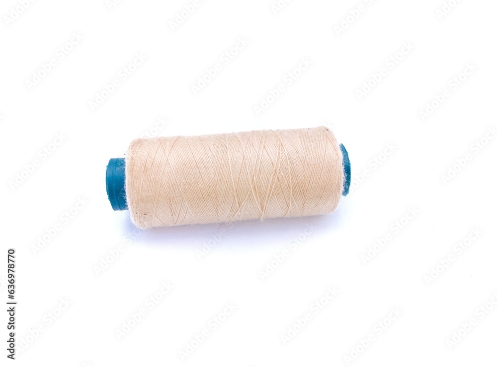 Beige color sewing thread isolated on white background, in soft-focus in the background. Beige color sewing thread isolated on white background, in soft-focus in the background.