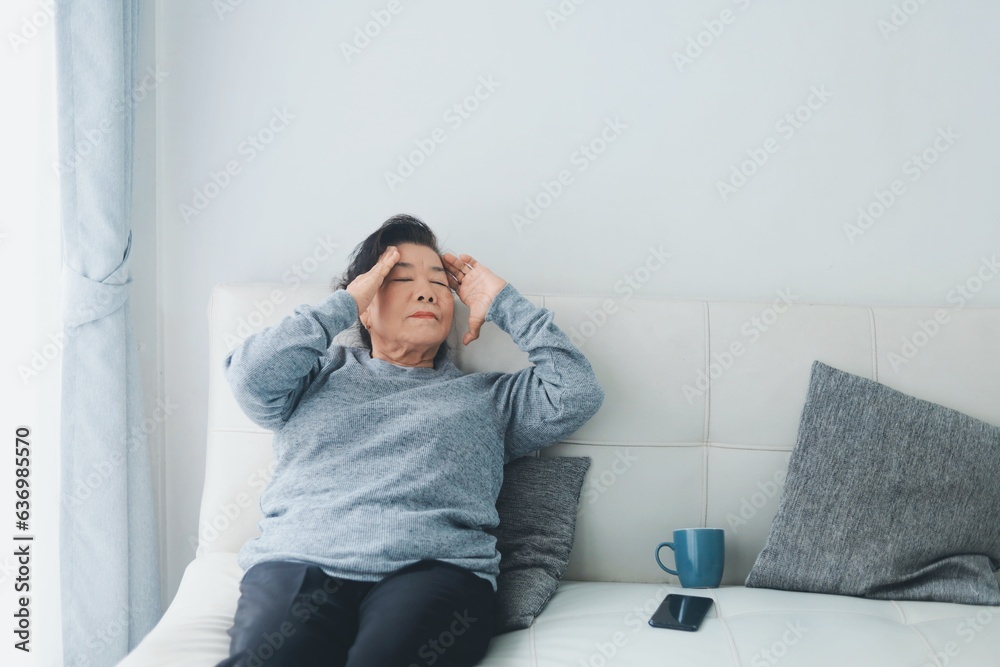 Fototapeta premium Asia senior woman lying on sofa feeling headache.