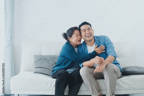 Happy Asian senior with smiling Asian man sitting sofa in living room ,Portrait Happy mother and son in living room ,Happiness family concept.